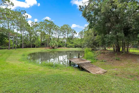 a view of a lake with lawn chairs under an umbrella