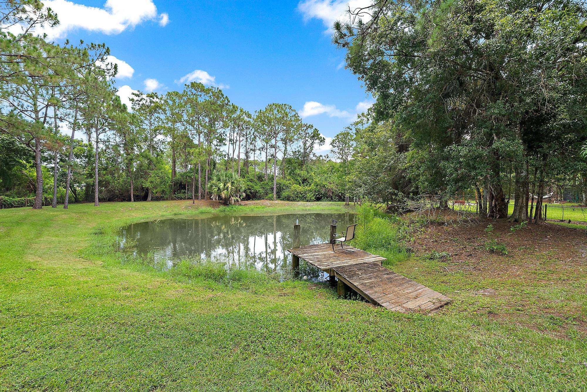 18222 126th Terrace North Jupiter, FL 33478 - Photo 3 of 22 a view of a lake with lawn chairs under an umbrella