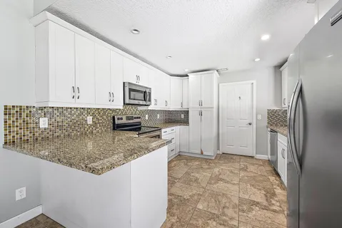 a kitchen with stainless steel appliances granite countertop a refrigerator and a stove top oven
