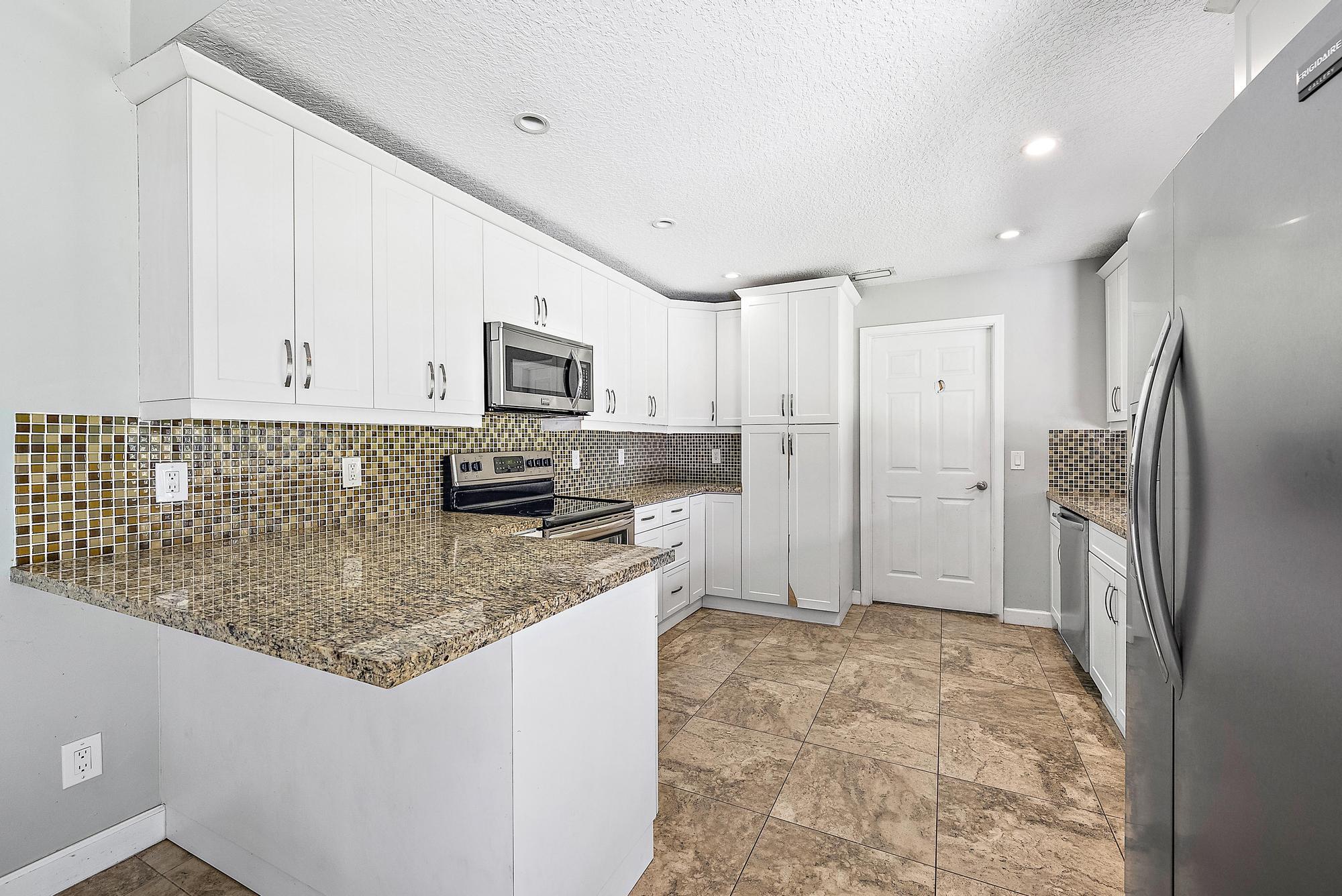 18222 126th Terrace North Jupiter, FL 33478 - Photo 4 of 22 a kitchen with stainless steel appliances granite countertop a refrigerator and a stove top oven
