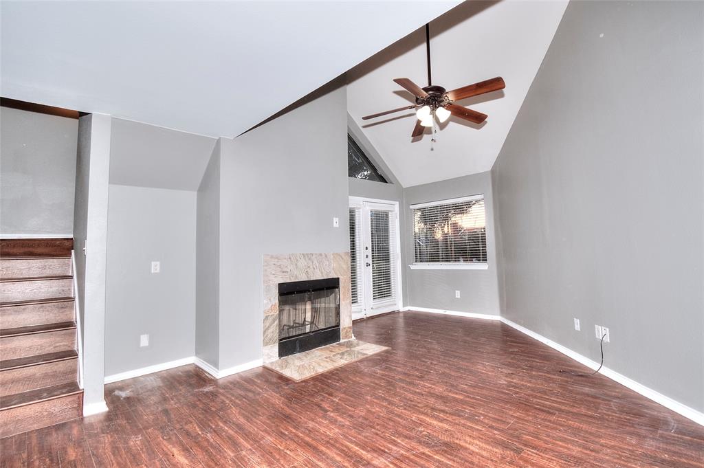 a view of a livingroom with a fireplace a ceiling fan and wooden floor