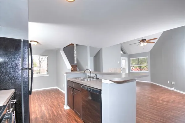 a kitchen with kitchen island granite countertop a sink cabinets and wooden floor