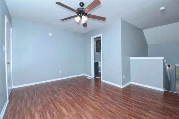 an empty room with wooden floor and a ceiling fan