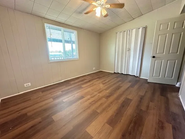 an empty room with wooden floor fan and windows