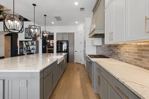 a large kitchen with stainless steel appliances granite countertop a sink a stove and a wooden floors