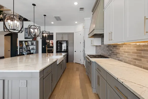a large kitchen with stainless steel appliances granite countertop a sink a stove and a wooden floors