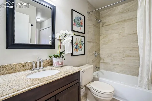a bathroom with a granite countertop sink a toilet and shower