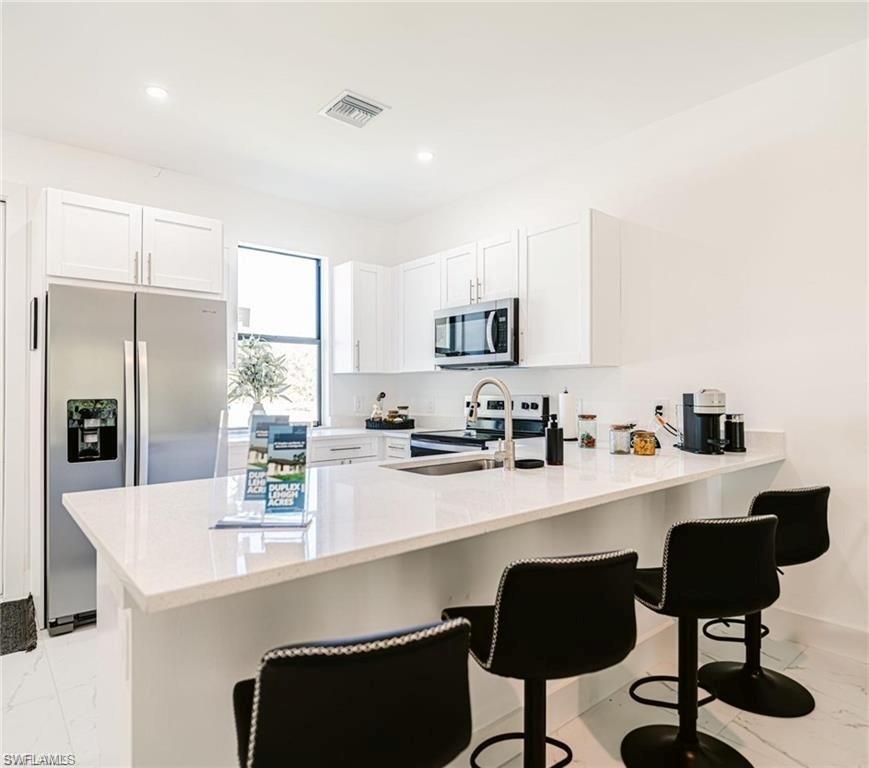 951 Graystone Avenue Lehigh Acres, FL 33974 - Photo 6 of 8 a kitchen with stainless steel appliances granite countertop a stove a sink a refrigerator white cabinets and chairs