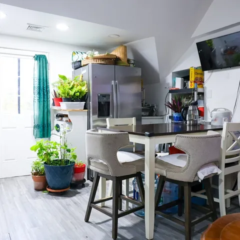 a kitchen with stainless steel appliances granite countertop a table chairs in it and wooden floors