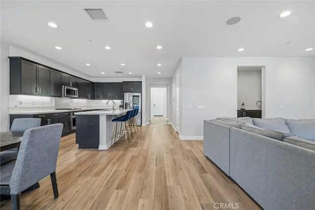 a living room with stainless steel appliances granite countertop furniture wooden floor and a view of kitchen