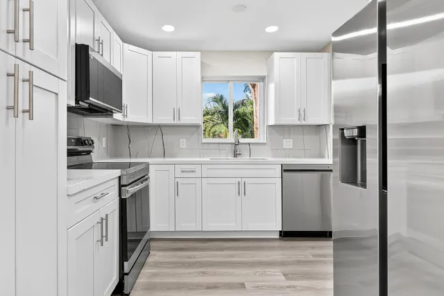 a kitchen with a sink stainless steel appliances and white cabinets