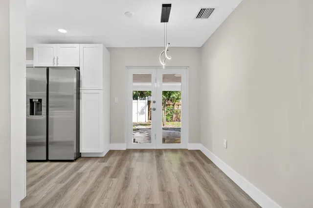an empty room with large windows and refrigerator