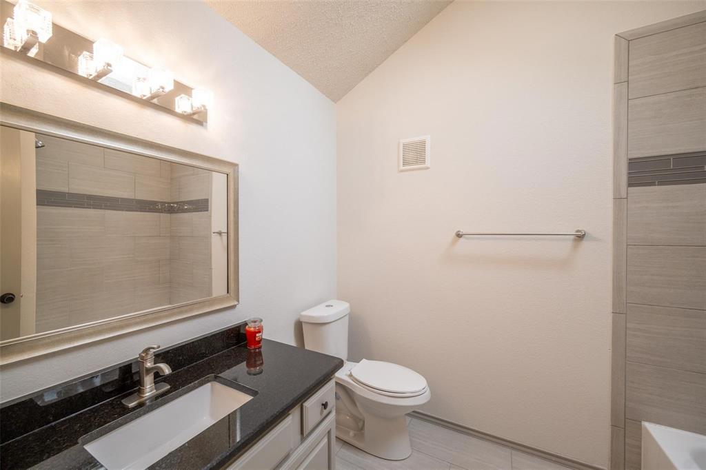 17735 Windflower Way, Unit 105 Dallas, TX 75252 - Photo 20 of 32 a bathroom with a granite countertop sink toilet and a mirror