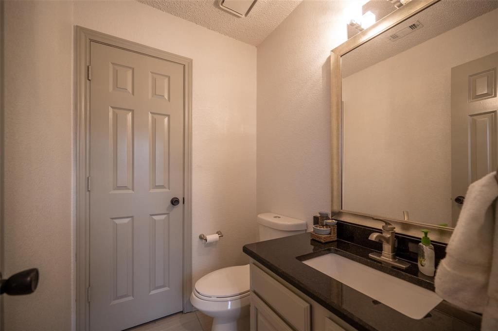 17735 Windflower Way, Unit 105 Dallas, TX 75252 - Photo 24 of 32 a bathroom with a granite countertop sink toilet and mirror
