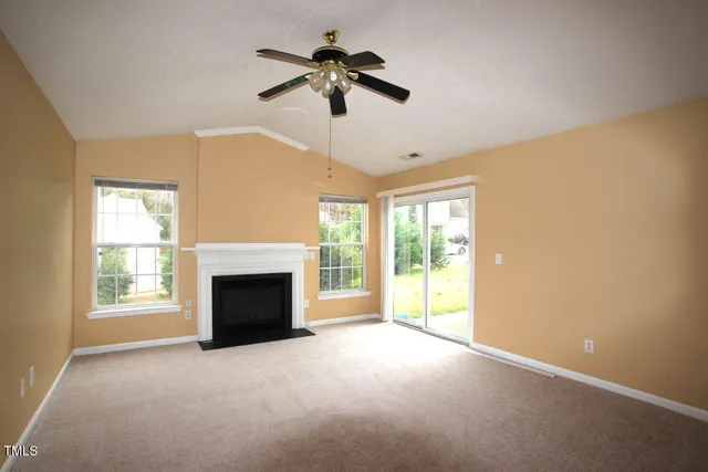 a view of empty room with fireplace and windows