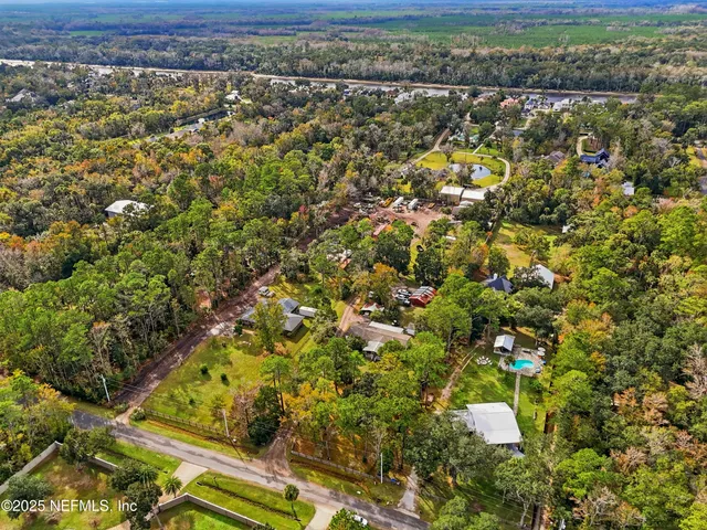 an aerial view of residential houses with outdoor space and trees