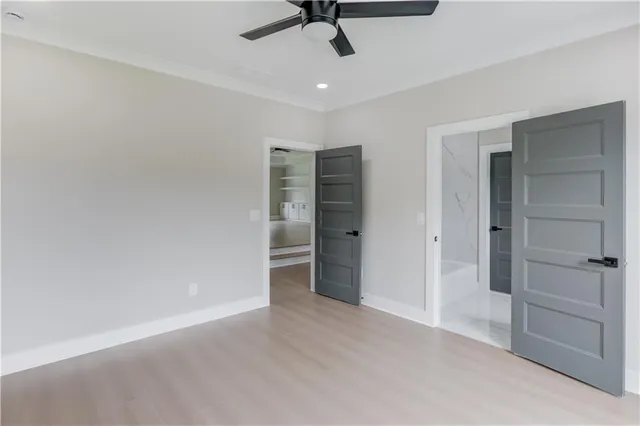an empty room with wooden floor a ceiling fan and windows
