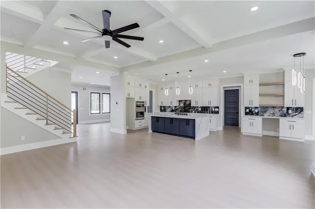 a large kitchen with stainless steel appliances kitchen island granite countertop a stove a sink dishwasher and a refrigerator with white cabinets