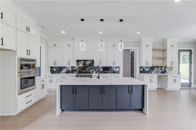 a large white kitchen with a large counter top appliances and cabinets