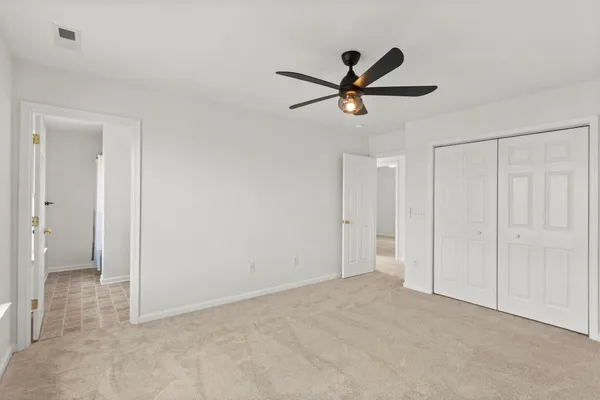 an empty room with windows and fan