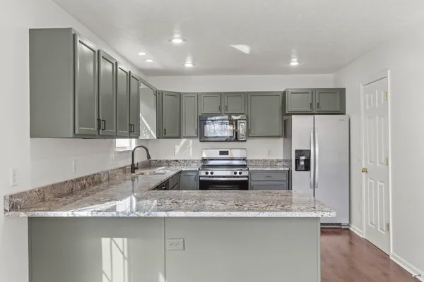 a kitchen with stainless steel appliances granite countertop a sink a stove and a refrigerator