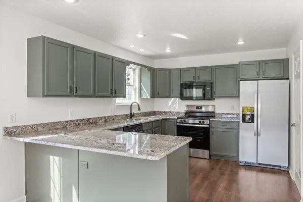a kitchen with kitchen island granite countertop stainless steel appliances a stove refrigerator sink and microwave