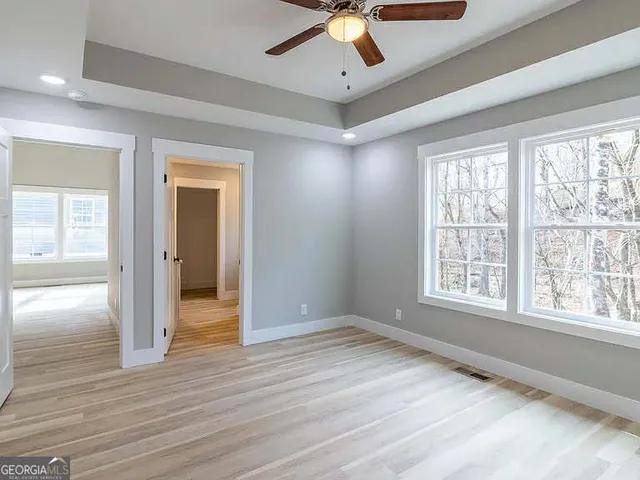a view of an empty room with a window and wooden floor