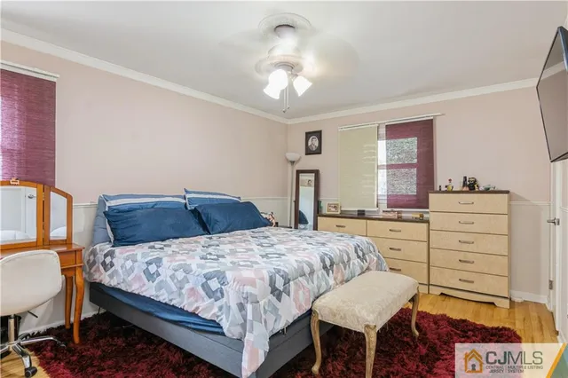 a bedroom with a bed a chandelier and a dresser