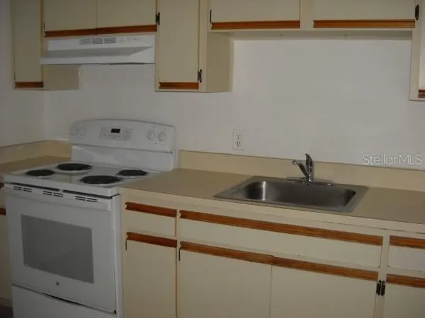 a view of a kitchen sink stove and cabinets