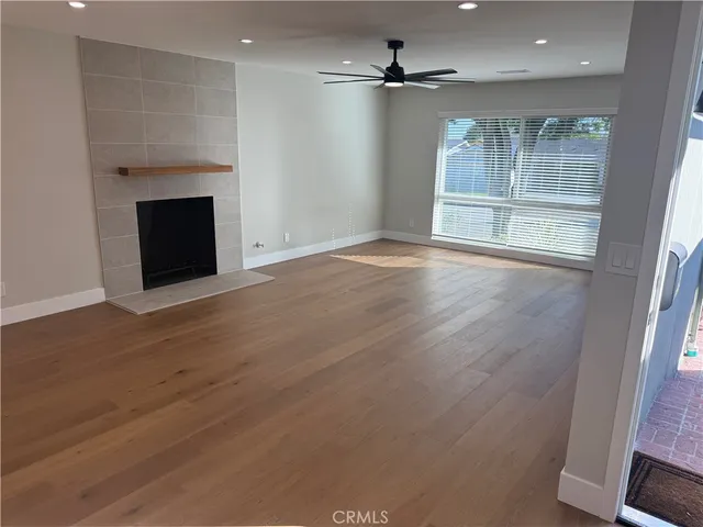an empty room with wooden floor fireplace and windows