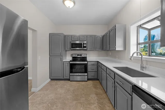 a kitchen with granite countertop a refrigerator stove and sink