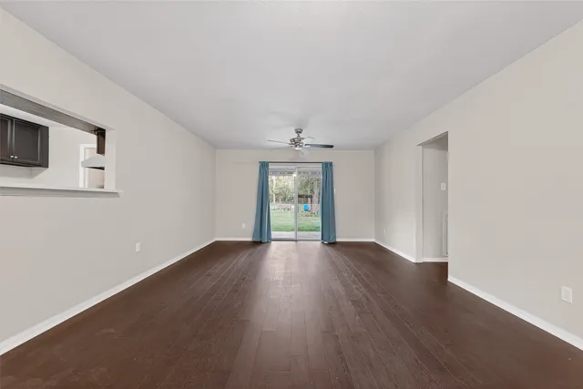 an empty room with wooden floor fan and windows