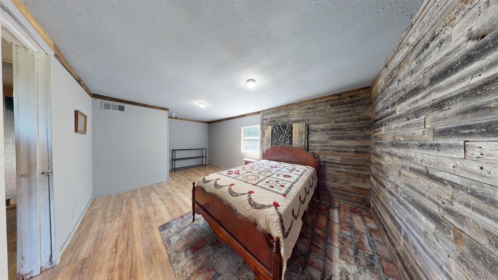 15415 Thunder Road Terrell, TX 75161 - Photo 14 of 21 Large Bedroom with ornamental molding, wooden walls, light wood-style flooring