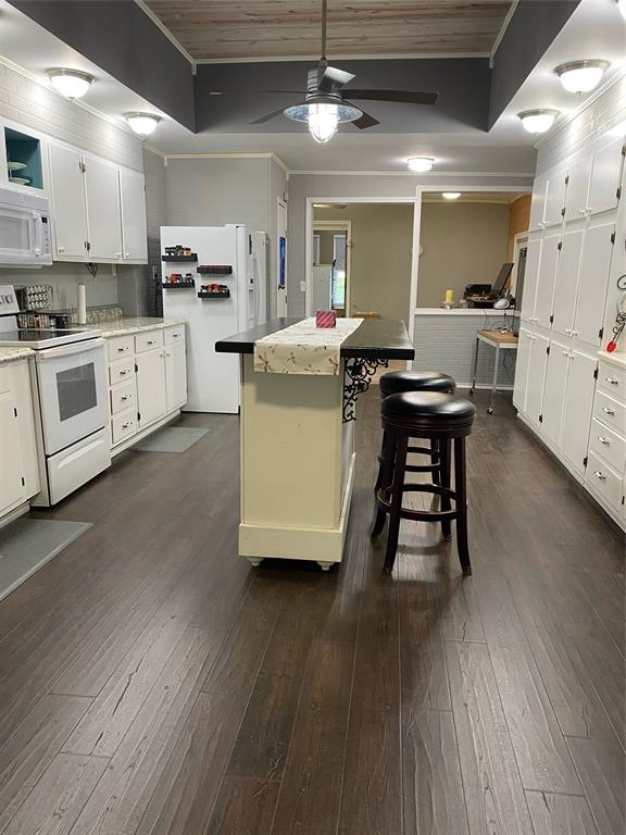 15415 Thunder Road Terrell, TX 75161 - Photo 8 of 21 Kitchen featuring a moveable island, breakfast nook, abundance of white cabinetry, and new dark wood like finished floors
