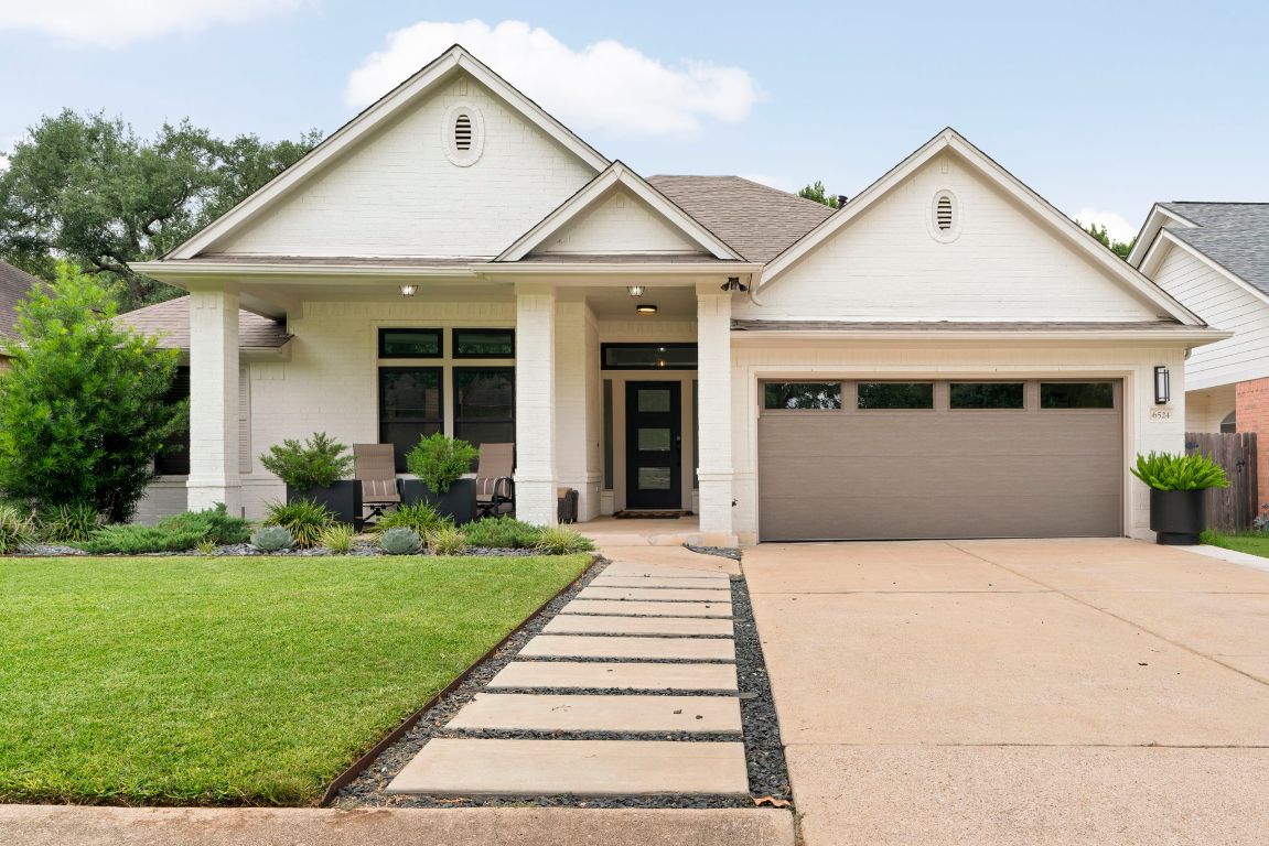a front view of a house with a yard and potted plants