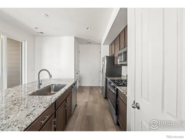 a kitchen with granite countertop a sink stove and refrigerator