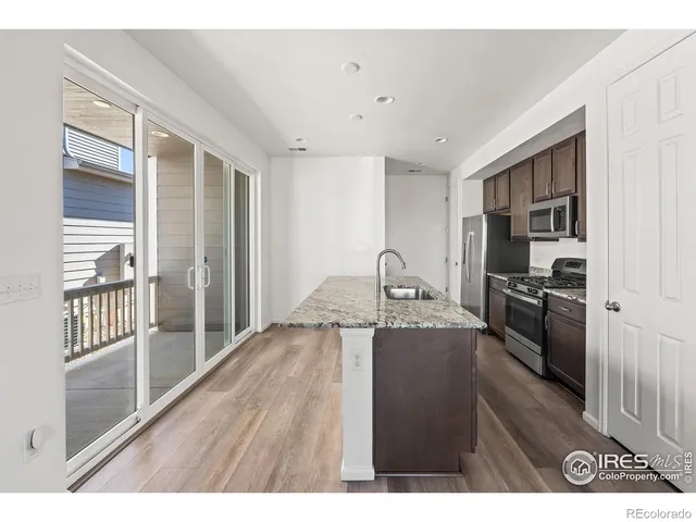a kitchen with kitchen island a counter top space a sink stainless steel appliances and cabinets