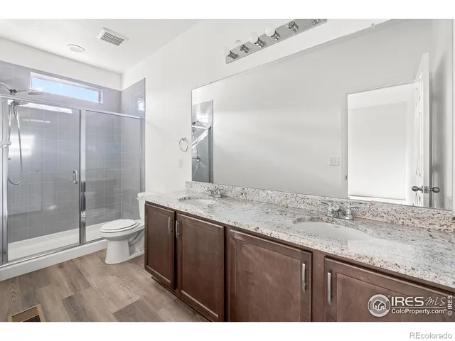 a bathroom with a granite countertop sink toilet a mirror and shower