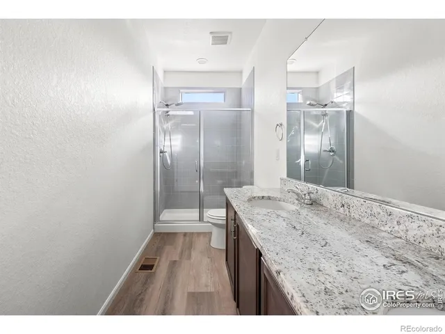 a bathroom with a granite countertop sink a mirror and a shower
