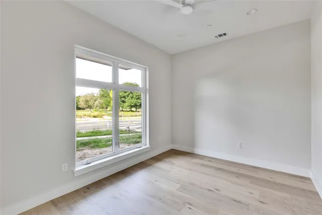 an empty room with wooden floor and windows