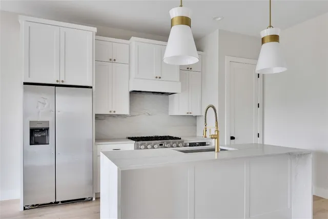 a kitchen with stainless steel appliances granite countertop a sink a stove and a refrigerator