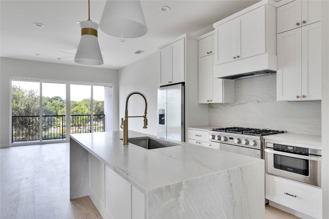 1937 East 38th 1/2 Street, Unit A Austin, TX 78723 - Photo 15 of 26 a kitchen with stainless steel appliances a sink a stove and white cabinets with wooden floor