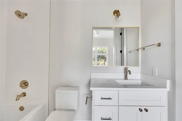 a bathroom with a granite countertop sink a toilet and shower