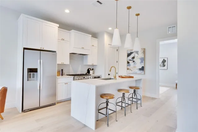 a kitchen with stainless steel appliances kitchen island a table chairs sink and cabinets
