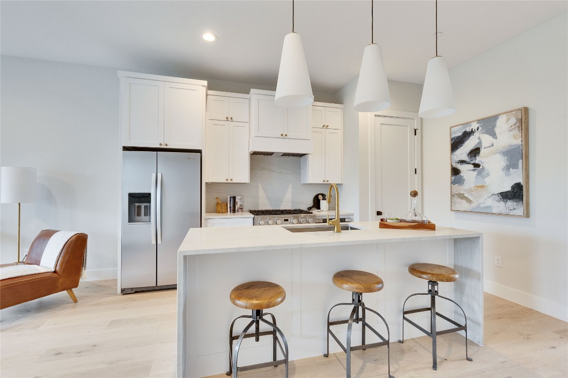 1937 East 38th 1/2 Street, Unit A Austin, TX 78723 - Photo 6 of 26 a kitchen with stainless steel appliances a stove a refrigerator and white cabinets with wooden chairs