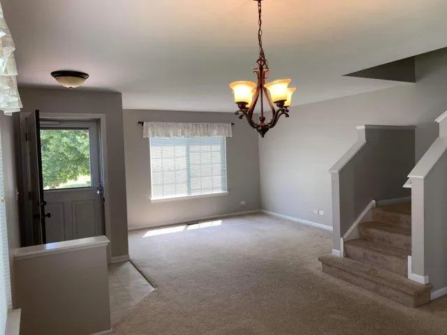 a view of a livingroom with a chandelier fan and windows