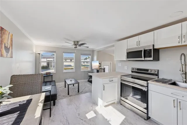 a kitchen with stainless steel appliances granite countertop a stove top oven a sink dishwasher and white cabinets with wooden floor