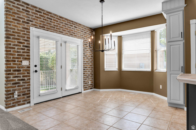 1417 Blacksmith Lane Draper, UT 84020 - Photo 12 of 57 Tiled flooring throughout this dining area, featuring a brick accent wall, French doors with white trim, a bay window configuration with white blinds, and a built-in white cabinet with black hardware