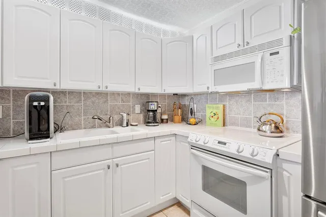 a kitchen with stainless steel appliances granite countertop white cabinets and a stove