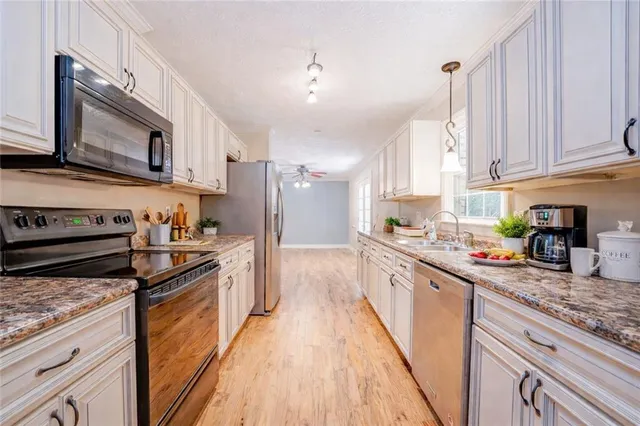a large kitchen with stainless steel appliances granite countertop a stove a sink dishwasher and a refrigerator